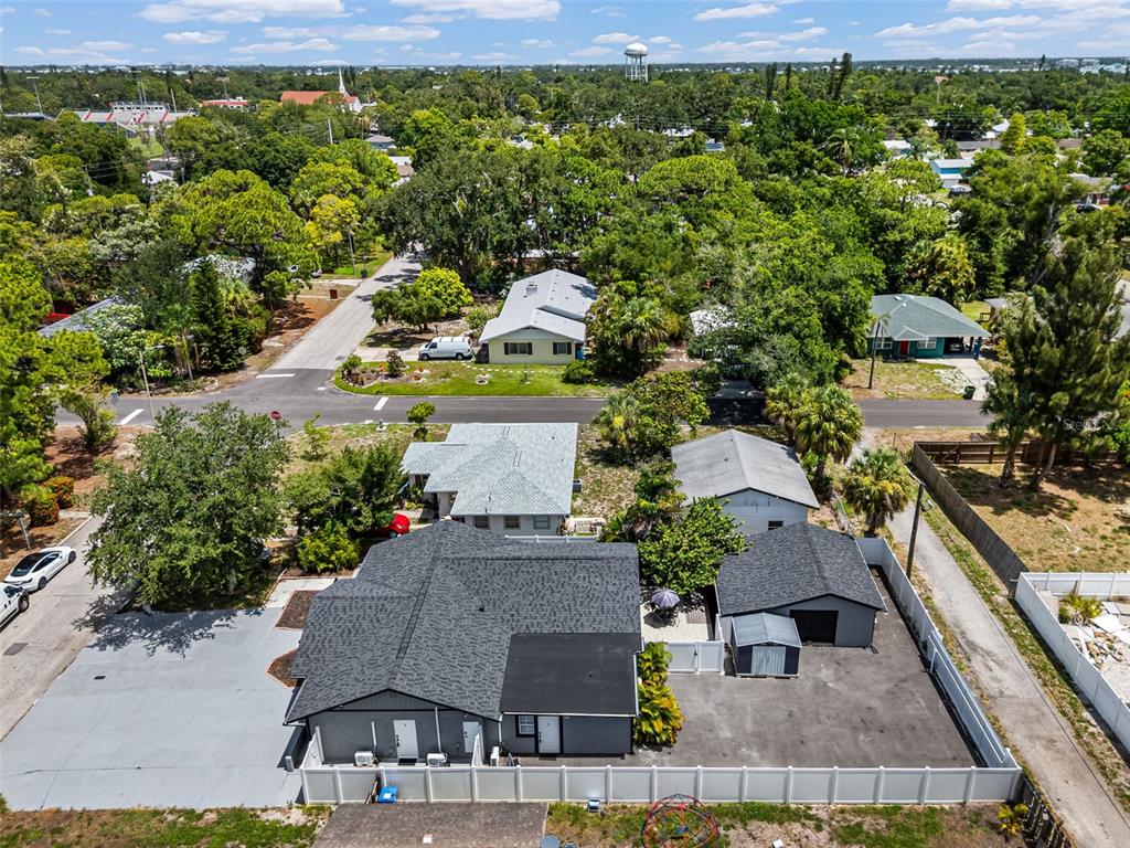 An aerial view shows a gray house with a dark roof, detached garage, and fenced yard — 1305 29TH STREET W, BRADENTON, FL