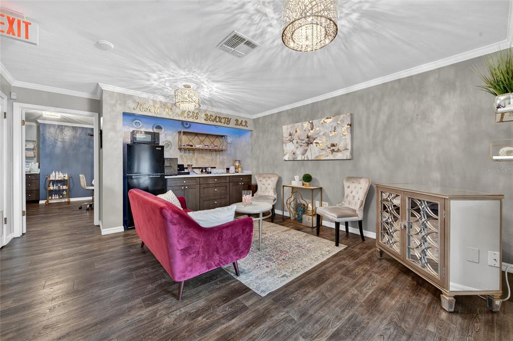 A waiting area features a pink sofa, two chairs, a small bar, and a mirrored cabinet — 555 W GRANADA BOULEVARD UNIT B7, ORMOND BEACH, FL