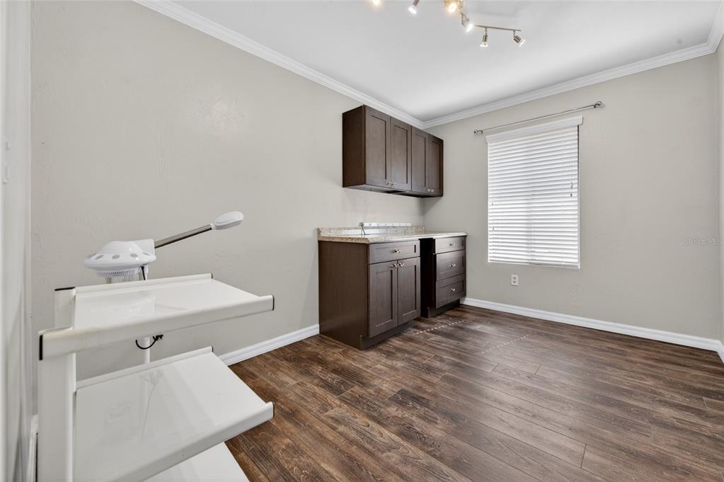 A small room with wood-look flooring, dark cabinetry, and a white facial steamer on a cart — 555 W GRANADA BOULEVARD UNIT B7, ORMOND BEACH, FL
