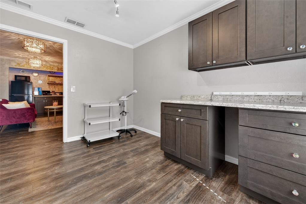 A room with dark wood cabinets, a granite countertop, and a rolling cart on wood flooring — 555 W GRANADA BOULEVARD UNIT B7, ORMOND BEACH, FL