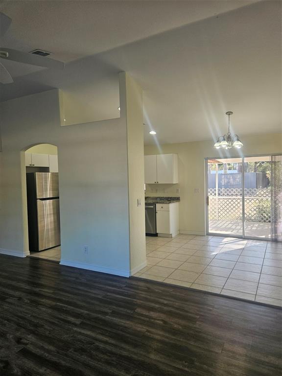 A kitchen with white cabinets and tile flooring is visible from a wood-floored living area — 4138 AZORA STREET, NORTH PORT, FL