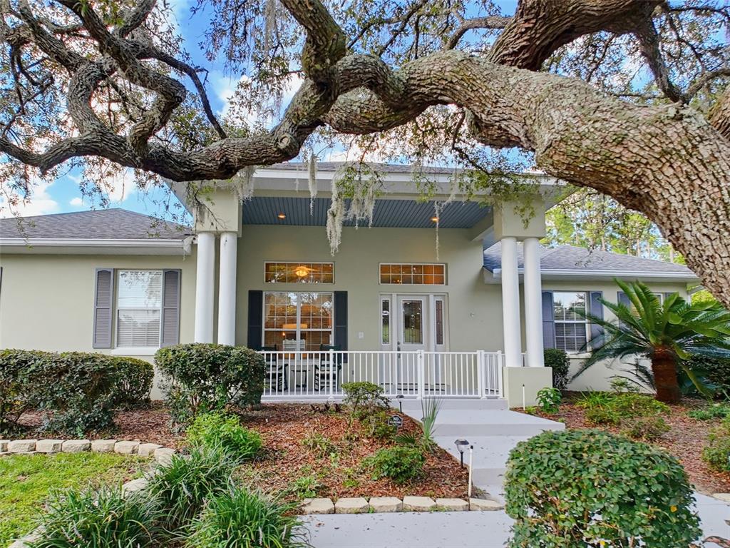 A single-story house with a covered front porch, white columns, and a large oak tree — 1709 W PINE RIDGE BOULEVARD, BEVERLY HILLS, FL