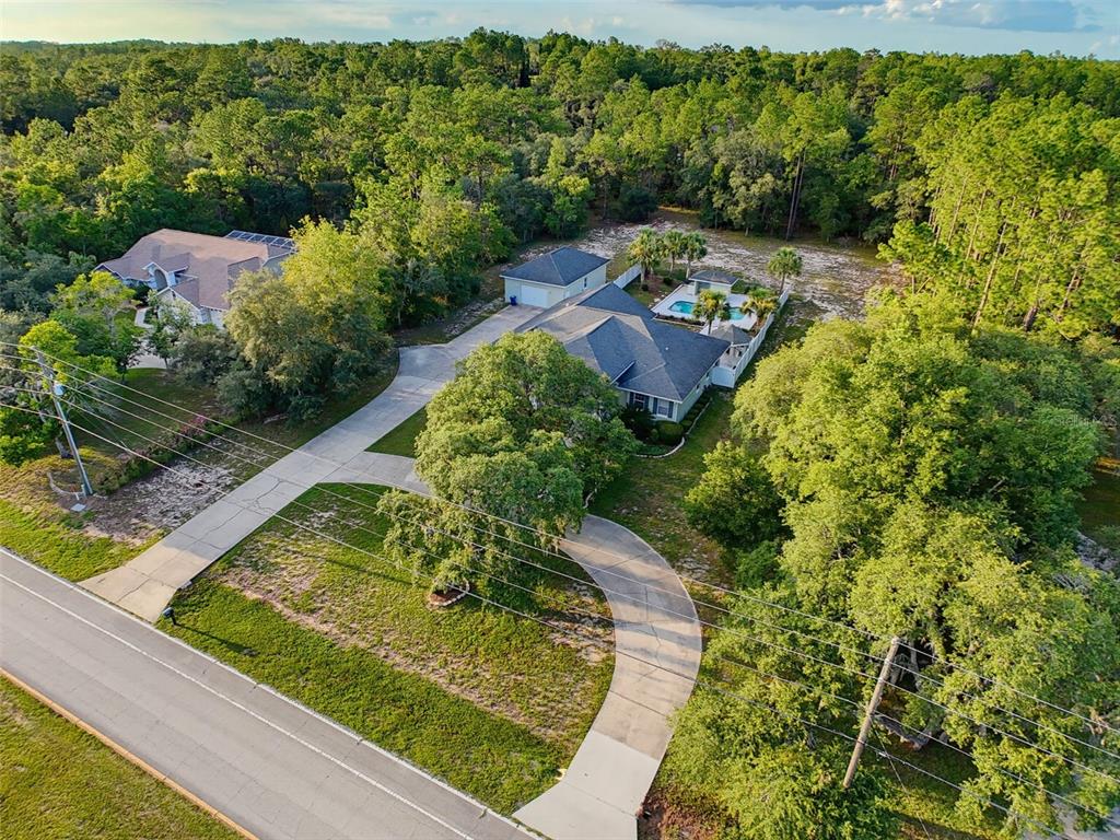 An aerial view shows a house with a pool, detached garage, and circular driveway — 1709 W PINE RIDGE BOULEVARD, BEVERLY HILLS, FL