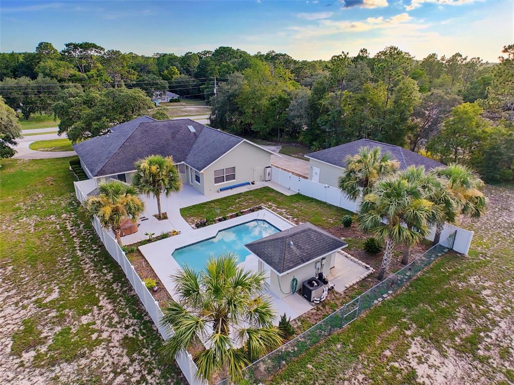 An aerial view of a house with a swimming pool, cabana, and fenced backyard — 1709 W PINE RIDGE BOULEVARD, BEVERLY HILLS, FL