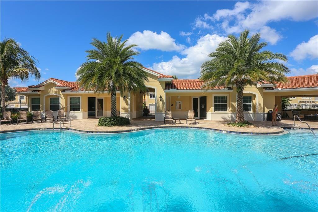 A swimming pool sits in front of a tan building with a red tile roof — 184 EXPLORER DRIVE, OSPREY, FL