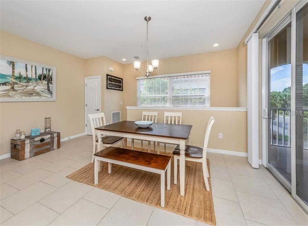 A dining room features a wooden table with a bench, chairs, and a tile floor — 184 EXPLORER DRIVE, OSPREY, FL