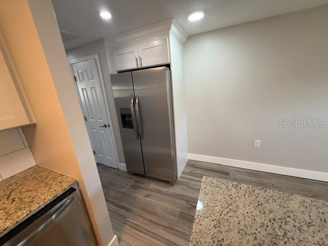 A stainless steel refrigerator is built into white cabinetry next to a doorway — 4933 ELKNER STREET, NEW PORT RICHEY, FL