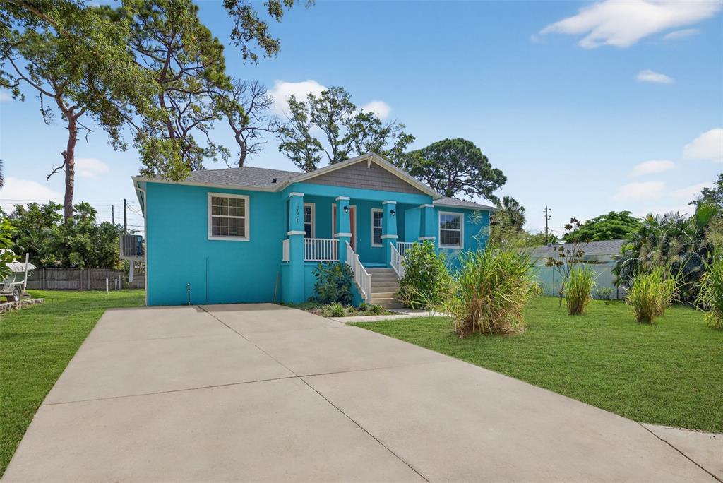 A bright blue single-story house features a front porch with white railings and a driveway — 2650 TIFTON STREET S, ST PETERSBURG, FL