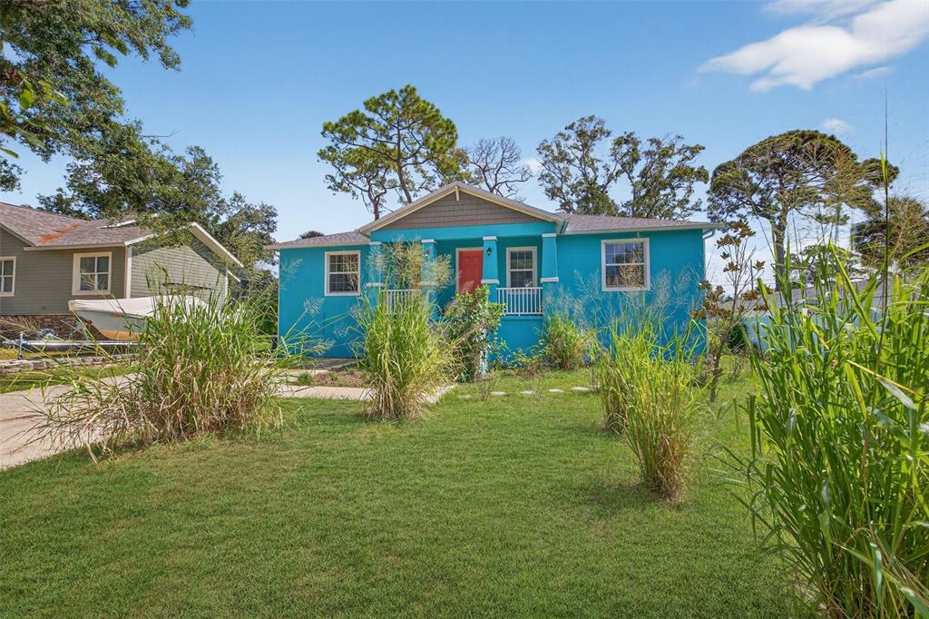 A bright blue single-story house with a red front door sits behind a grassy yard — 2650 TIFTON STREET S, ST PETERSBURG, FL