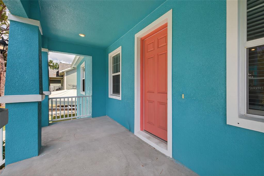 A covered porch with bright blue walls and a coral-colored front door — 2650 TIFTON STREET S, ST PETERSBURG, FL
