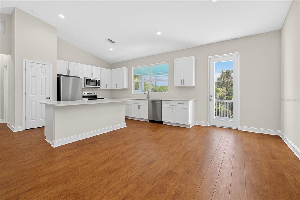 A kitchen with white cabinets, stainless steel appliances, and wood-look flooring opens to a patio — 2650 TIFTON STREET S, ST PETERSBURG, FL