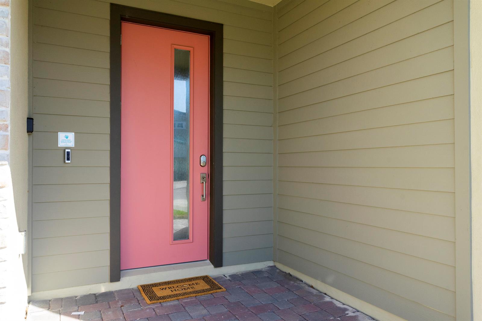 A pink front door with a vertical glass panel sits on a brick porch — 405 Strand Drive, Melbourne Beach FL 32951, MELBOURNE BEACH, FL
