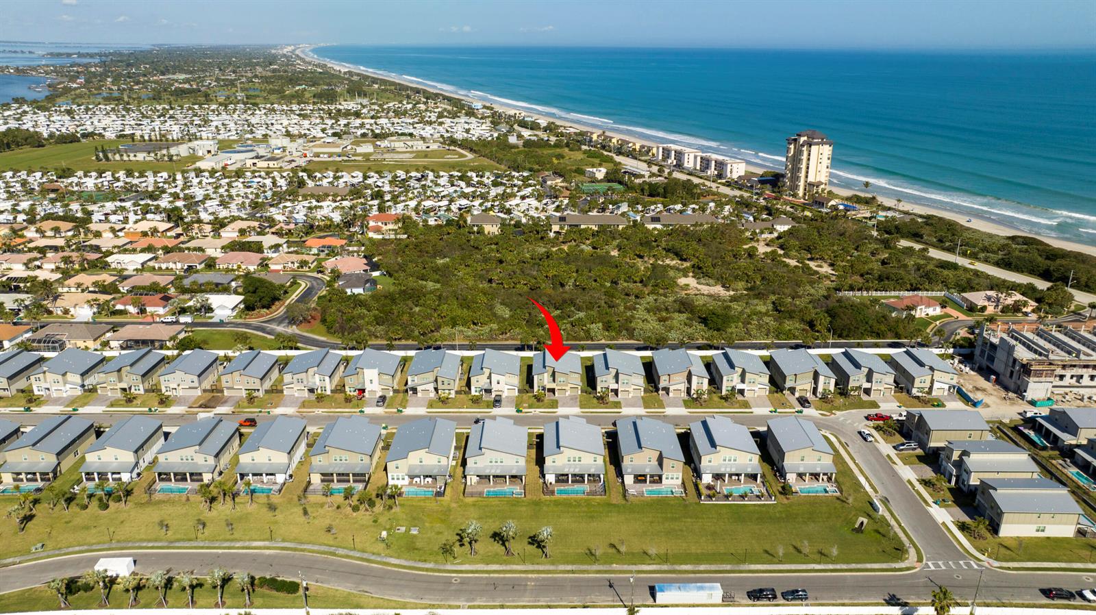 An aerial view shows a row of modern townhomes with pools near a coastal beach — 405 Strand Drive, Melbourne Beach FL 32951, MELBOURNE BEACH, FL