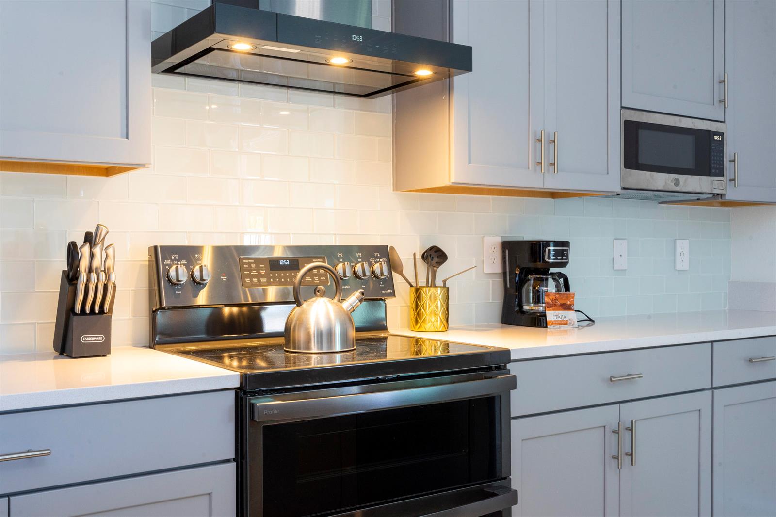 A modern kitchen features gray cabinets, white subway tile backsplash, and stainless steel appliances — 405 Strand Drive, Melbourne Beach FL 32951, MELBOURNE BEACH, FL