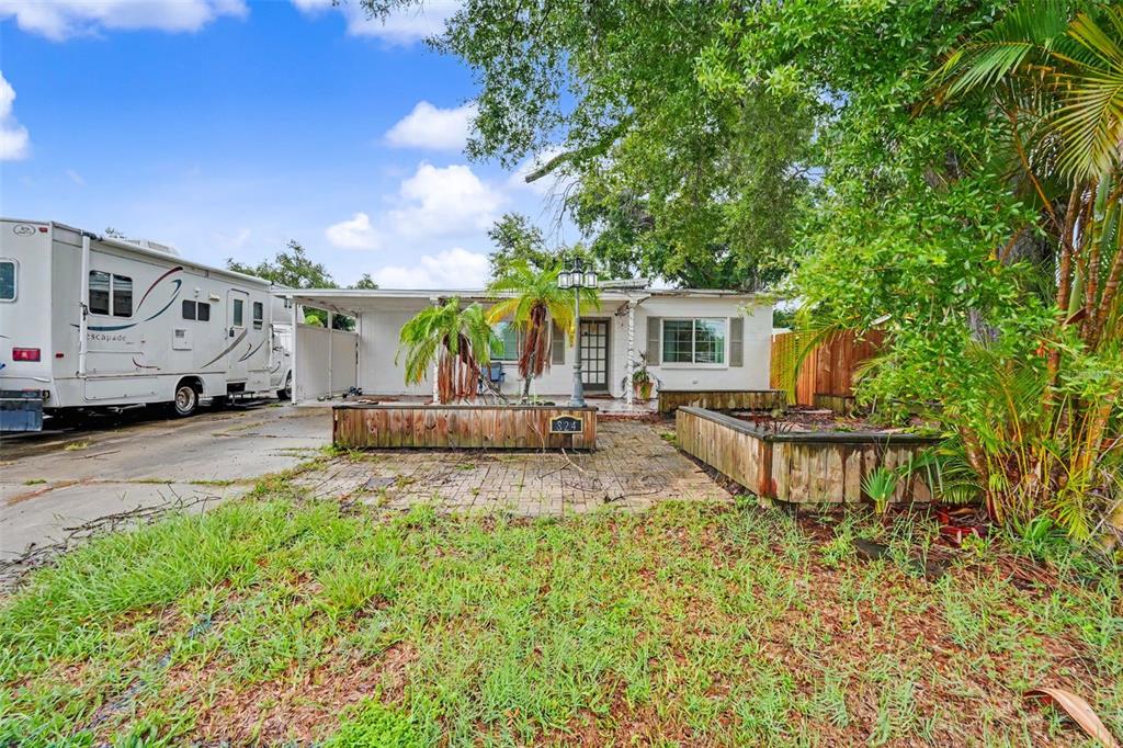 A single-story house with a white exterior, a paved front patio, and a parked RV — 824 67TH STREET S, ST PETERSBURG, FL