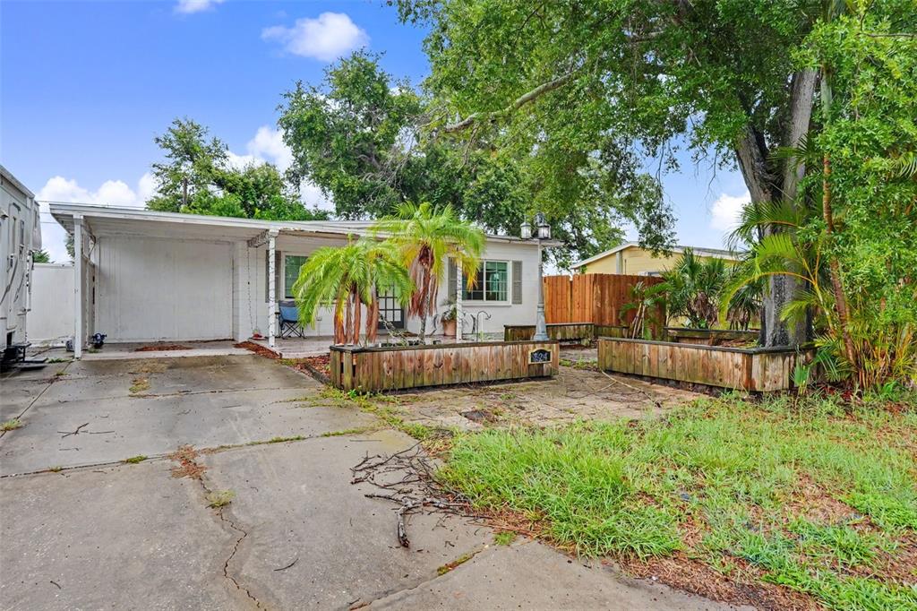 A single-story house features a concrete driveway, a carport, and wooden planter boxes out front — 824 67TH STREET S, ST PETERSBURG, FL