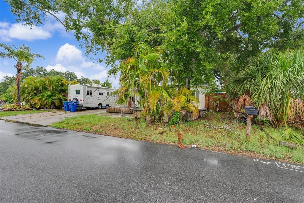 A white recreational vehicle is parked on a concrete driveway next to a residential lot — 824 67TH STREET S, ST PETERSBURG, FL