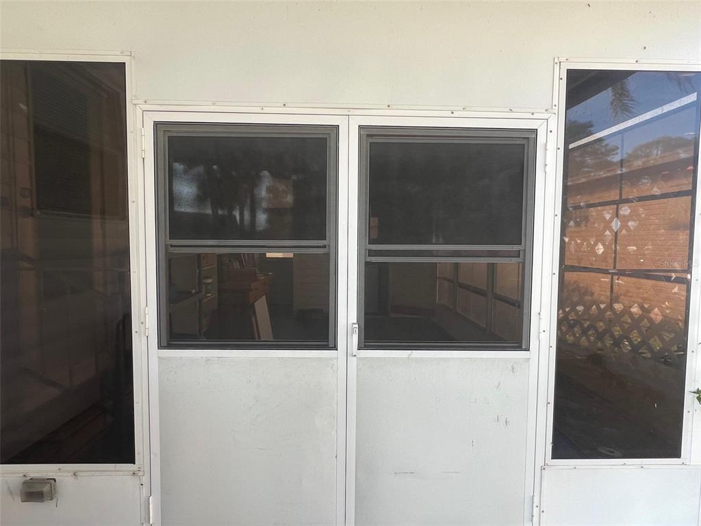 A white-framed screen door with two glass windows is set within a screened enclosure — 354 KING PALM STREET, LARGO, FL