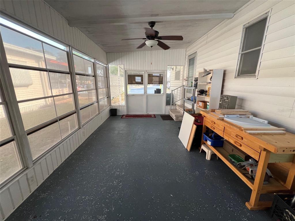A sunroom features a ceiling fan, large windows, a workbench, and a painted concrete floor — 354 KING PALM STREET, LARGO, FL