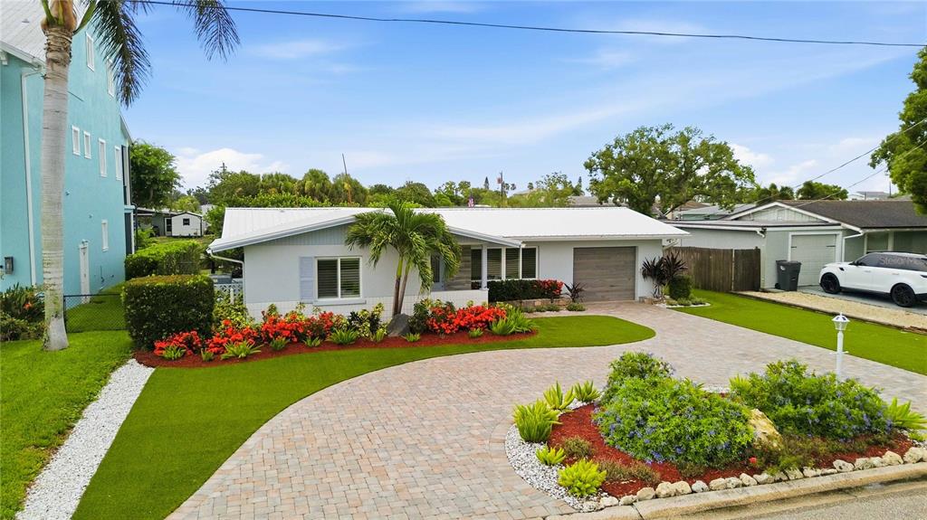 A single-story house with a paved circular driveway, manicured lawn, and vibrant landscaping — 720 IXORA AVENUE, ELLENTON, FL