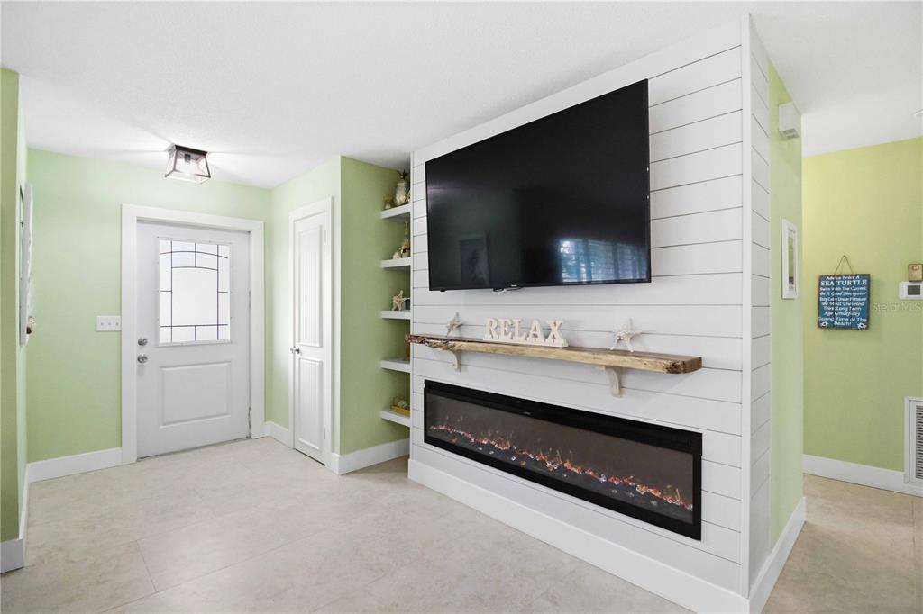 A living room features a shiplap fireplace wall with a mounted television and live-edge mantel — 720 IXORA AVENUE, ELLENTON, FL