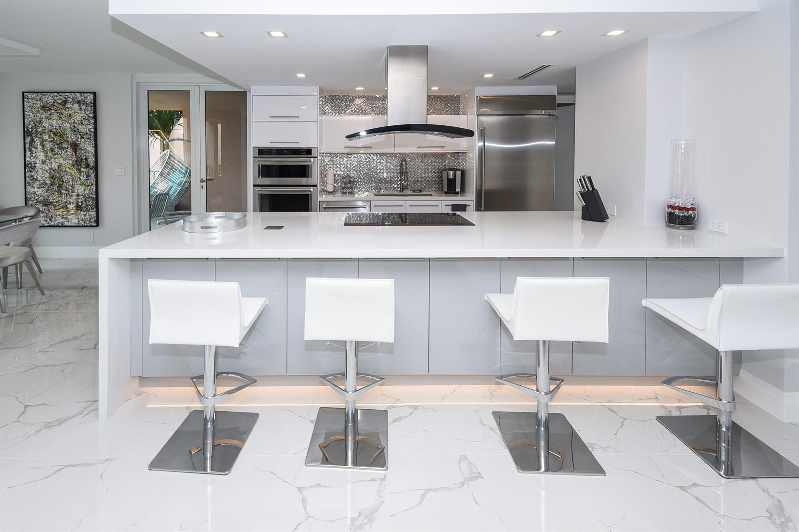 A modern kitchen features a large white island, gray cabinetry, and white marble-patterned flooring — 120 SE 5th Avenue, Boca Raton FL 33432, BOCA RATON, FL