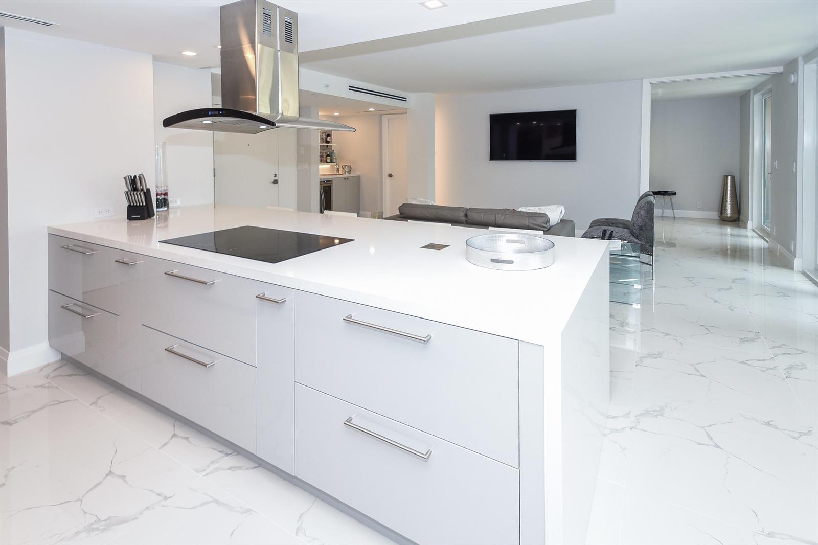 A modern kitchen island with a cooktop and white cabinetry sits on a marble floor — 120 SE 5th Avenue, Boca Raton FL 33432, BOCA RATON, FL