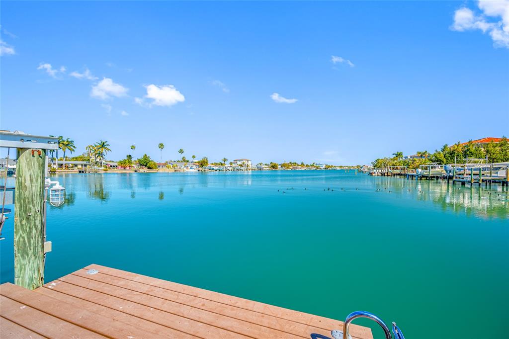 A wooden dock overlooks a calm, turquoise canal lined with houses and boat slips — 17161 2ND STREET E, NORTH REDINGTON BEACH, FL