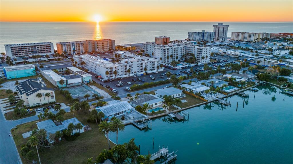 An aerial view of a coastal neighborhood with apartment buildings, houses, and a waterfront canal — 17161 2ND STREET E, NORTH REDINGTON BEACH, FL