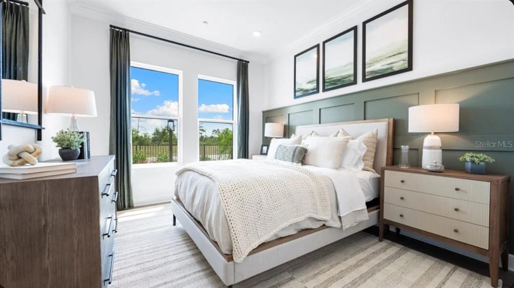 A bedroom features a green paneled accent wall, a bed with neutral bedding, and windows — 10594 ECLIPSE STREET, SARASOTA, FL