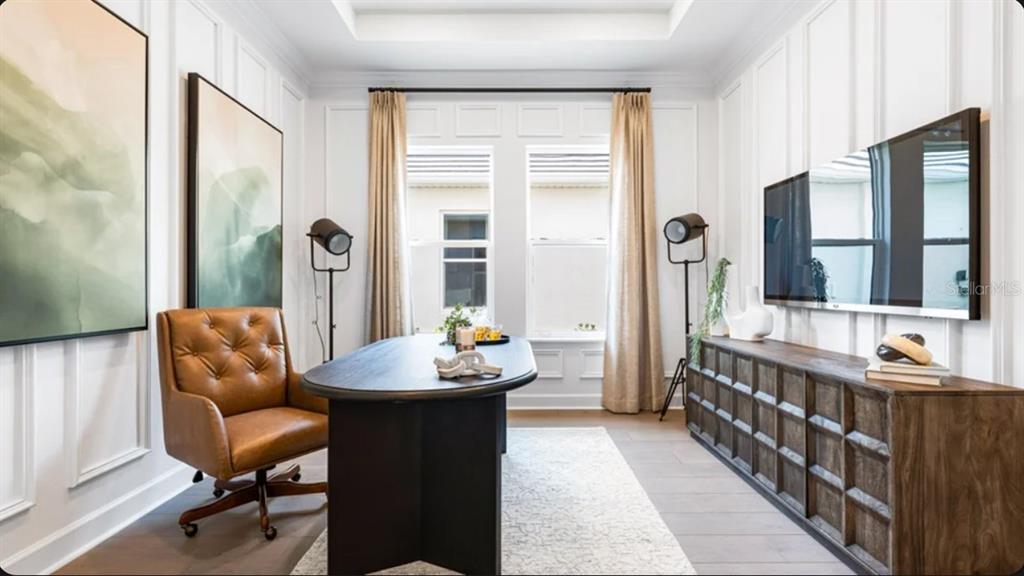 A home office features a dark oval desk, leather chair, wall paneling, and a media console — 10594 ECLIPSE STREET, SARASOTA, FL