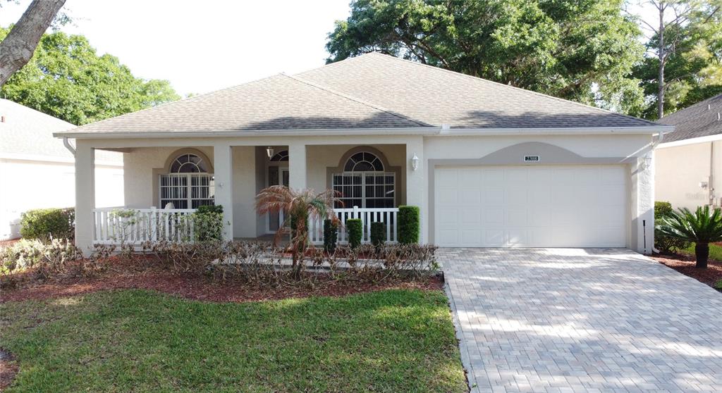 A single-story house with a beige stucco exterior, a covered front porch, and a paved driveway — 2308 TWICKINGHAM COURT, CLERMONT, FL