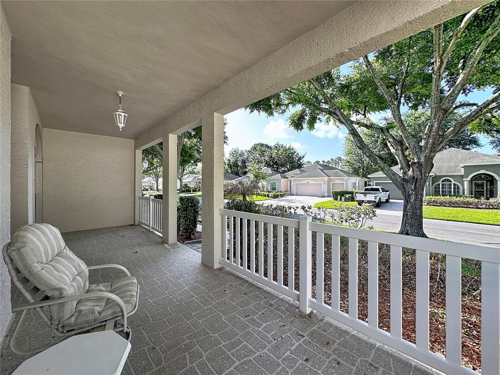 A covered porch with a white railing overlooks a suburban street and neighboring houses — 2308 TWICKINGHAM COURT, CLERMONT, FL