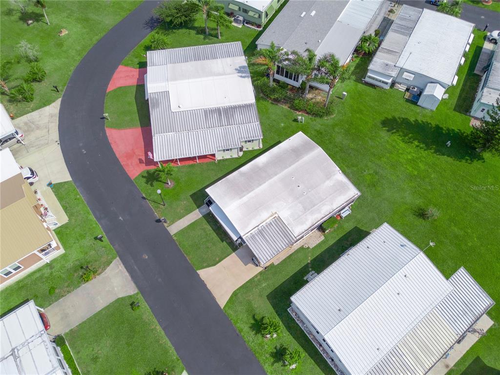 An aerial view shows several mobile homes with metal roofs situated on a grassy lot — 315 BEAVER LANE, HAINES CITY, FL
