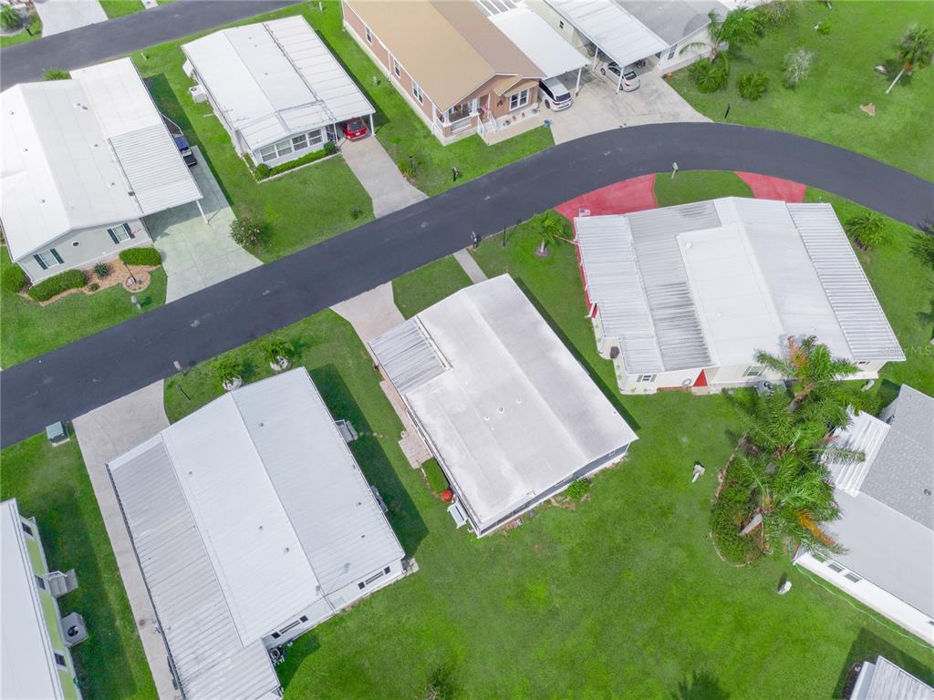 An aerial view shows several mobile homes with metal roofs situated along a curved road — 315 BEAVER LANE, HAINES CITY, FL