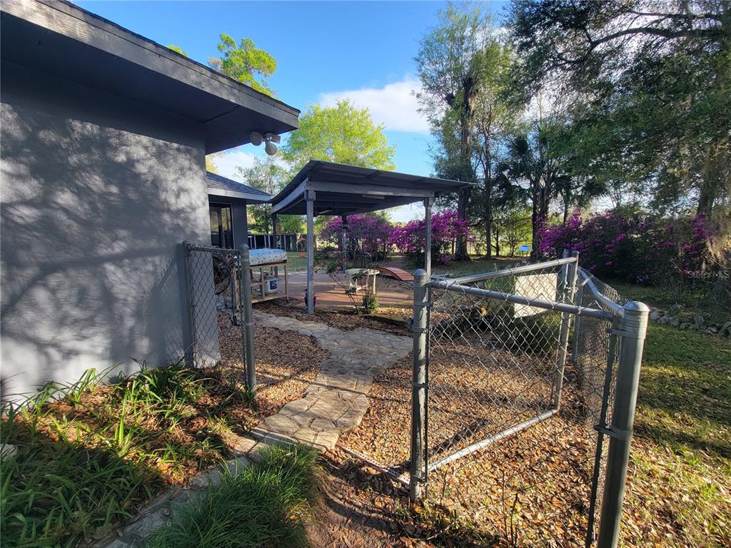 A fenced backyard features a stone path leading to a covered patio area with landscaping — 8028 SE 129TH PLACE, SUMMERFIELD, FL