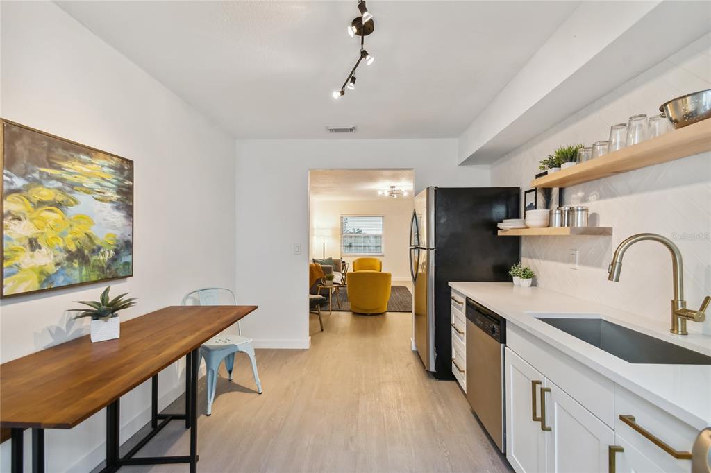 A kitchen with white cabinets, a black refrigerator, and a wooden dining table — 6422 S ADELIA AVENUE, TAMPA, FL