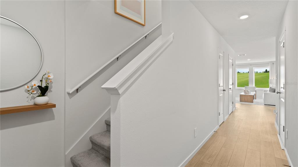 A hallway with light wood flooring leads to a living area with a view outside — 1066 TWINS STREET, DAVENPORT, FL