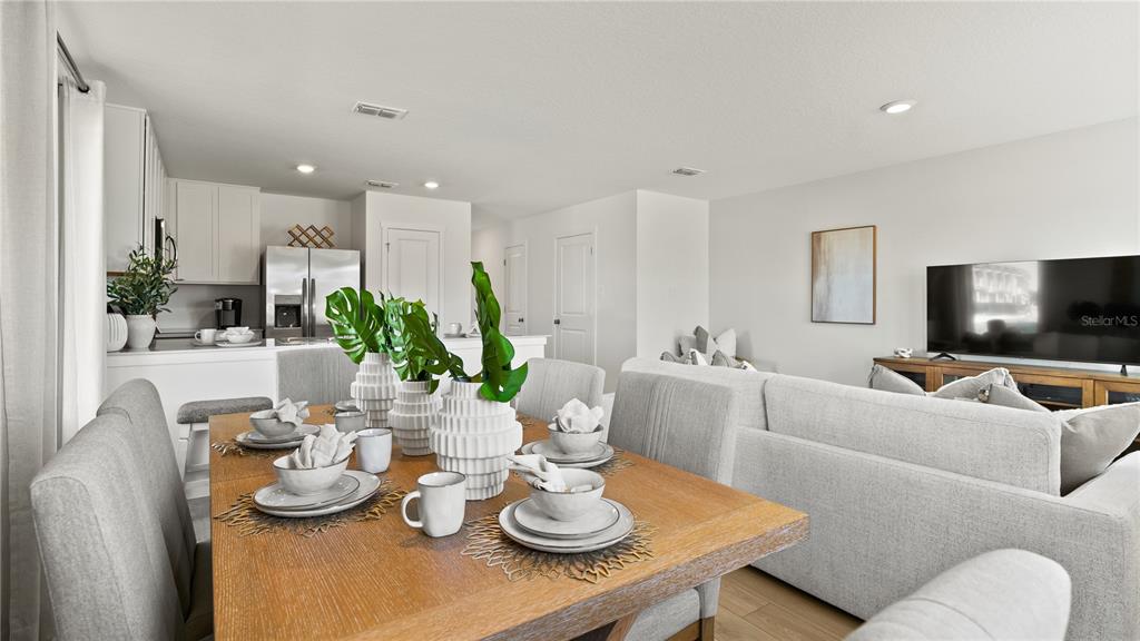 A dining area with a wooden table and chairs opens into a living room and kitchen — 1066 TWINS STREET, DAVENPORT, FL