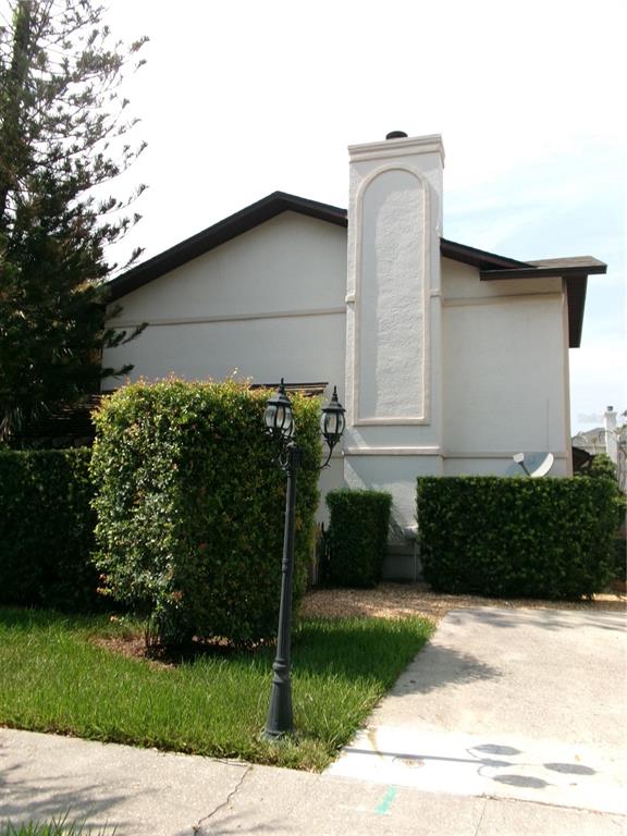A beige house exterior features a prominent chimney, a lamp post, and manicured green hedges — 1061 ARAGON AVENUE UNIT 1061, WINTER PARK, FL