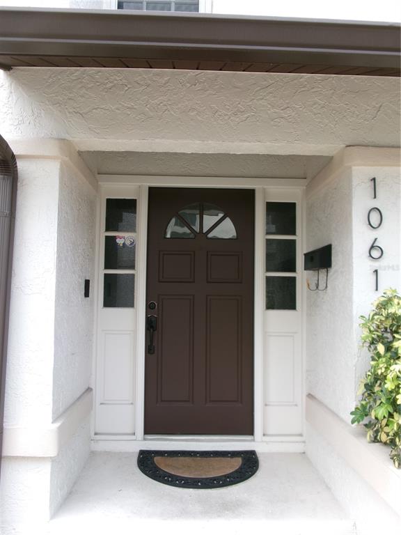 A brown front door with a semi-circular window is flanked by sidelights under a porch — 1061 ARAGON AVENUE UNIT 1061, WINTER PARK, FL