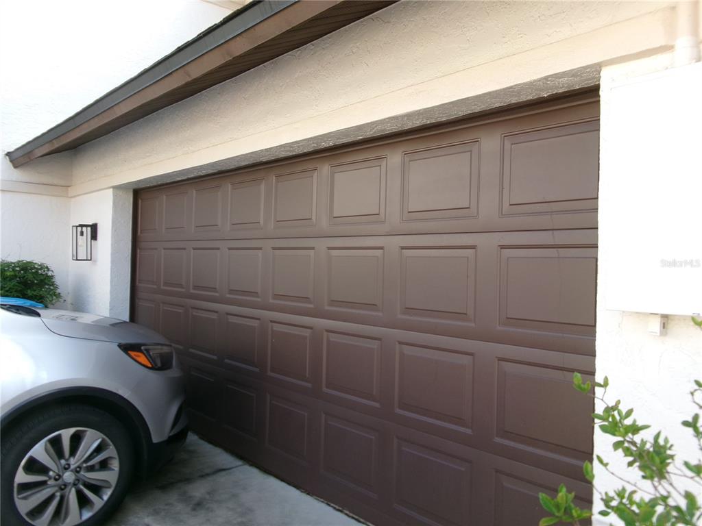 A brown sectional garage door is installed on the exterior of a white stucco home — 1061 ARAGON AVENUE UNIT 1061, WINTER PARK, FL