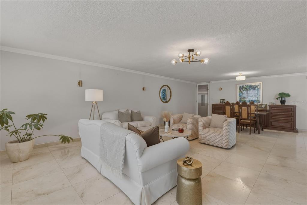 A living and dining area features white tile floors, neutral furniture, and a modern chandelier — 15 CALLE TAFT UNIT 202, SAN JUAN, PR
