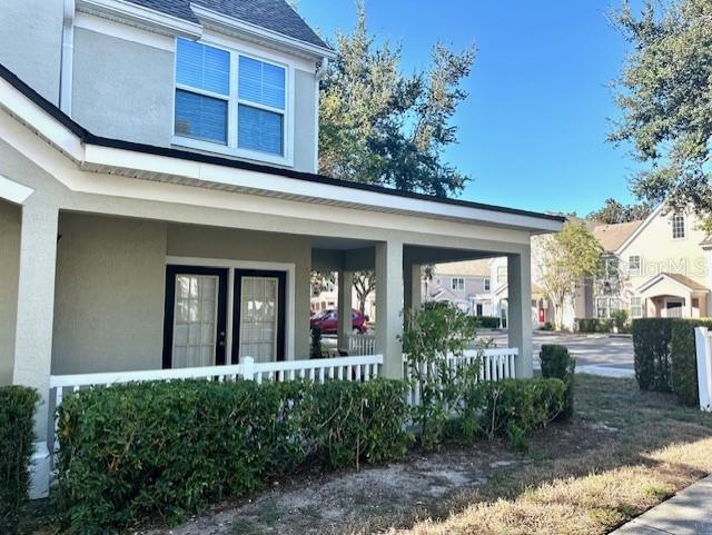 A two-story house exterior features a covered front porch with a white railing and hedges — 3324 PARKCHESTER SQUARE BOULEVARD UNIT 102, ORLANDO, FL
