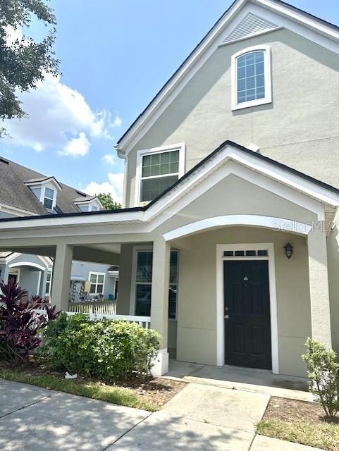 The exterior of a light green two-story house features a covered porch and dark door — 3324 PARKCHESTER SQUARE BOULEVARD UNIT 102, ORLANDO, FL