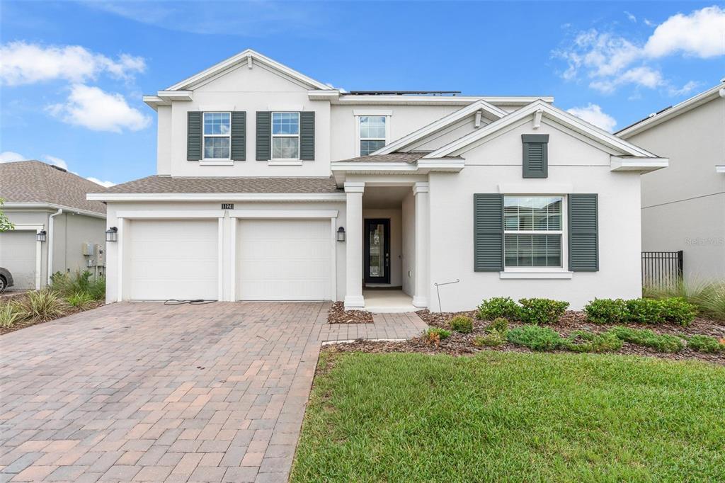 A two-story house with a white stucco facade, dark shutters, and a two-car garage — 11941 LANGUAGE WAY, ORLANDO, FL