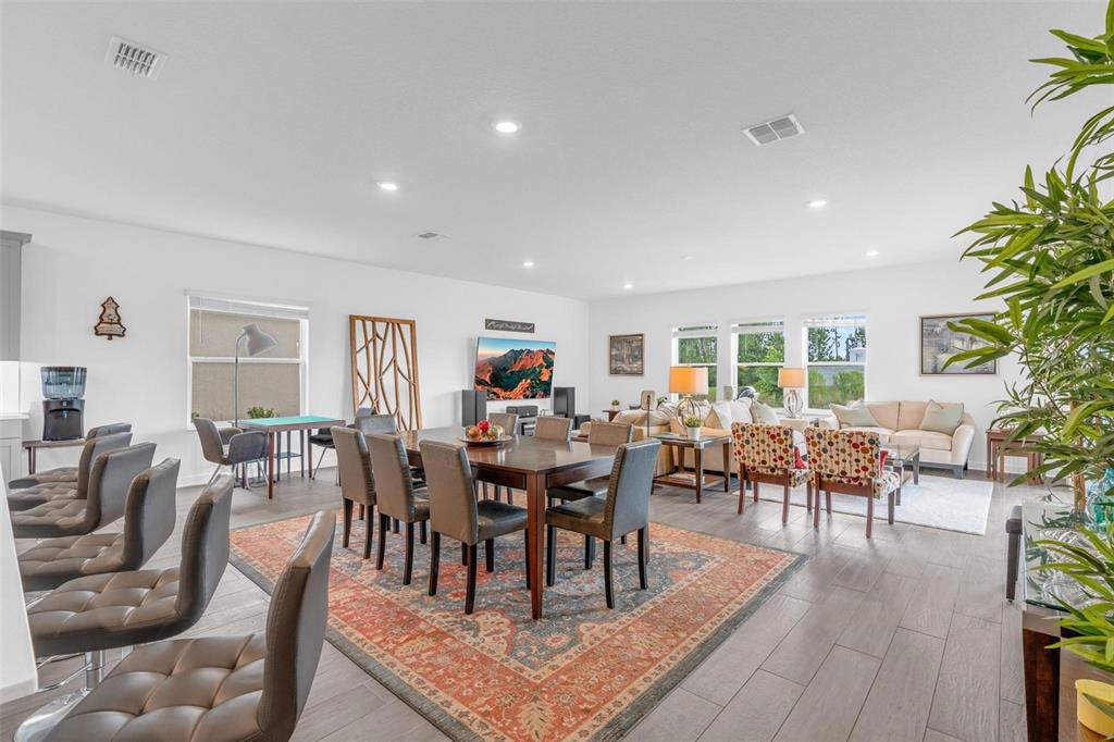 An open-concept living and dining area features tile flooring, a large rug, and neutral walls — 11941 LANGUAGE WAY, ORLANDO, FL