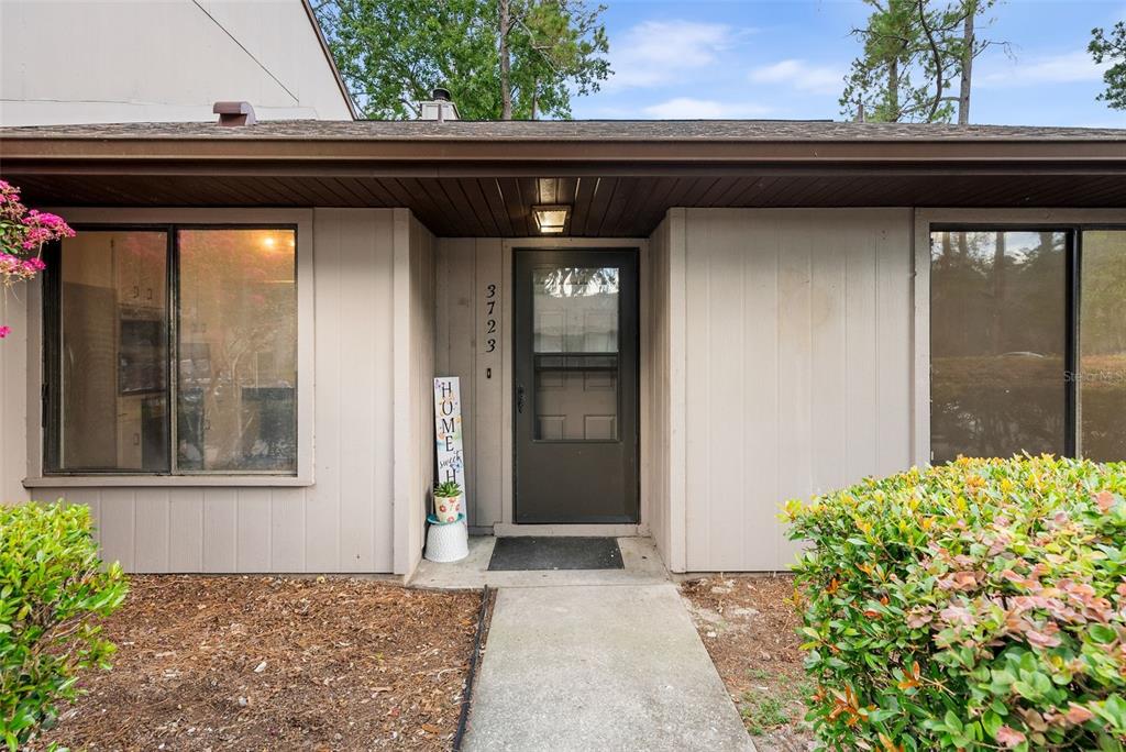 The exterior of a house features a brown front door, beige siding, and a walkway — 3723 NW 55TH PLACE, GAINESVILLE, FL