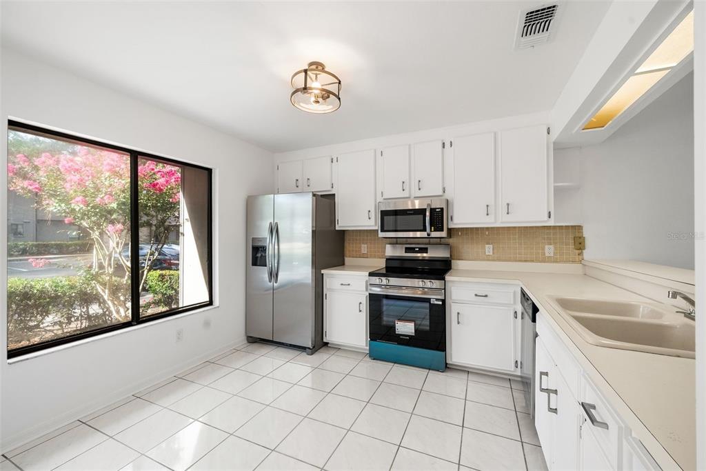 A kitchen with white cabinets, stainless steel appliances, tile flooring, and a large window — 3723 NW 55TH PLACE, GAINESVILLE, FL