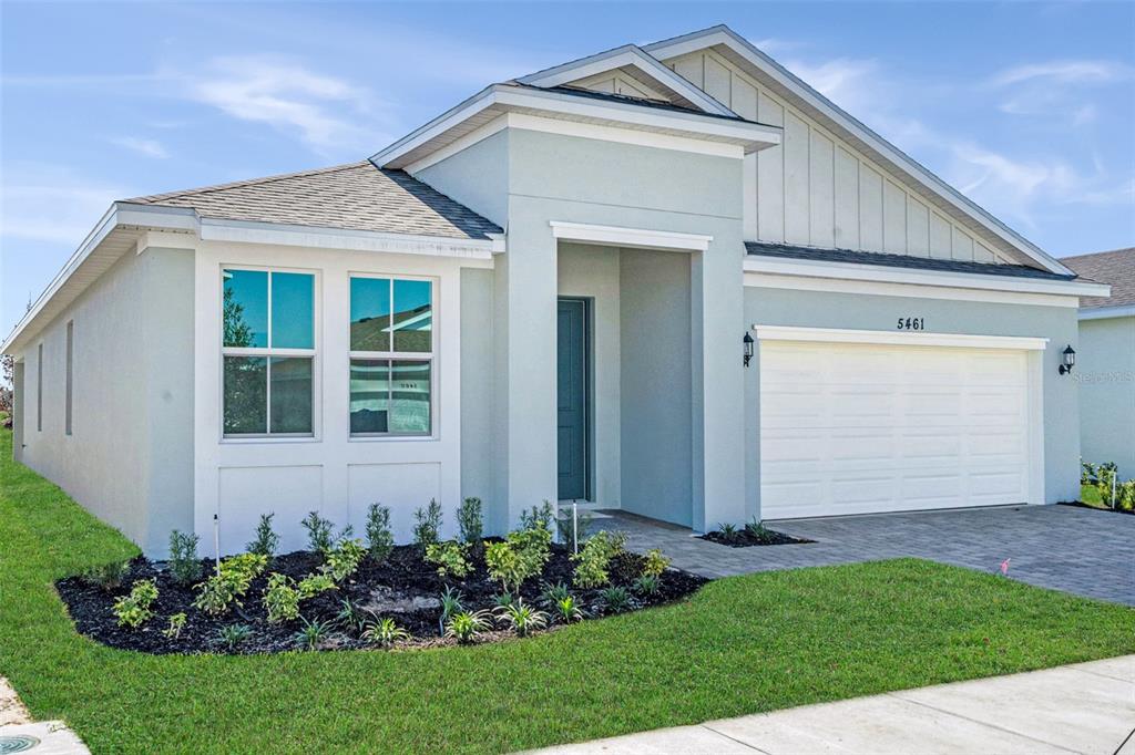 A single-story house with a light-colored stucco exterior, a two-car garage, and a landscaped yard — 5461 NW CAMBERLY COURT, PORT ST LUCIE, FL